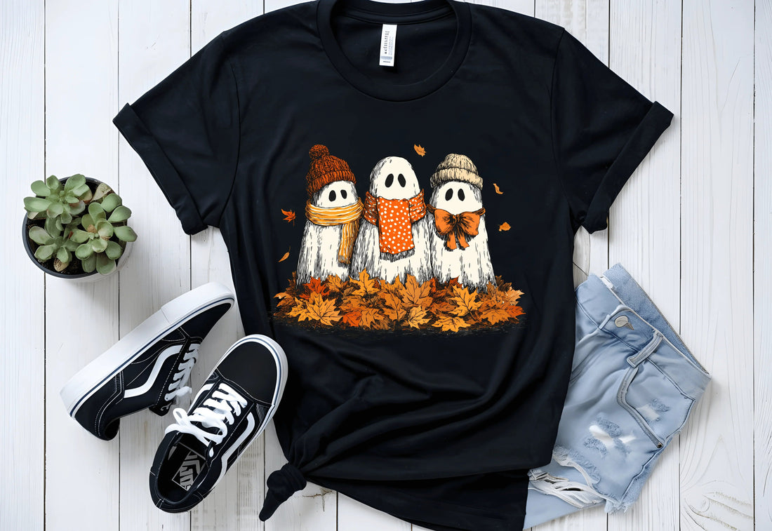 Cute ghosts in scarves on black t-shirt amidst autumn leaves, perfect for Halloween fashion.