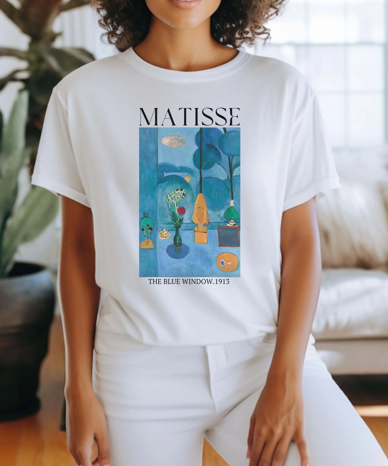 A woman wearing a Matisse t-shirt featuring 'The Blue Window.1913' as part of her art collection.