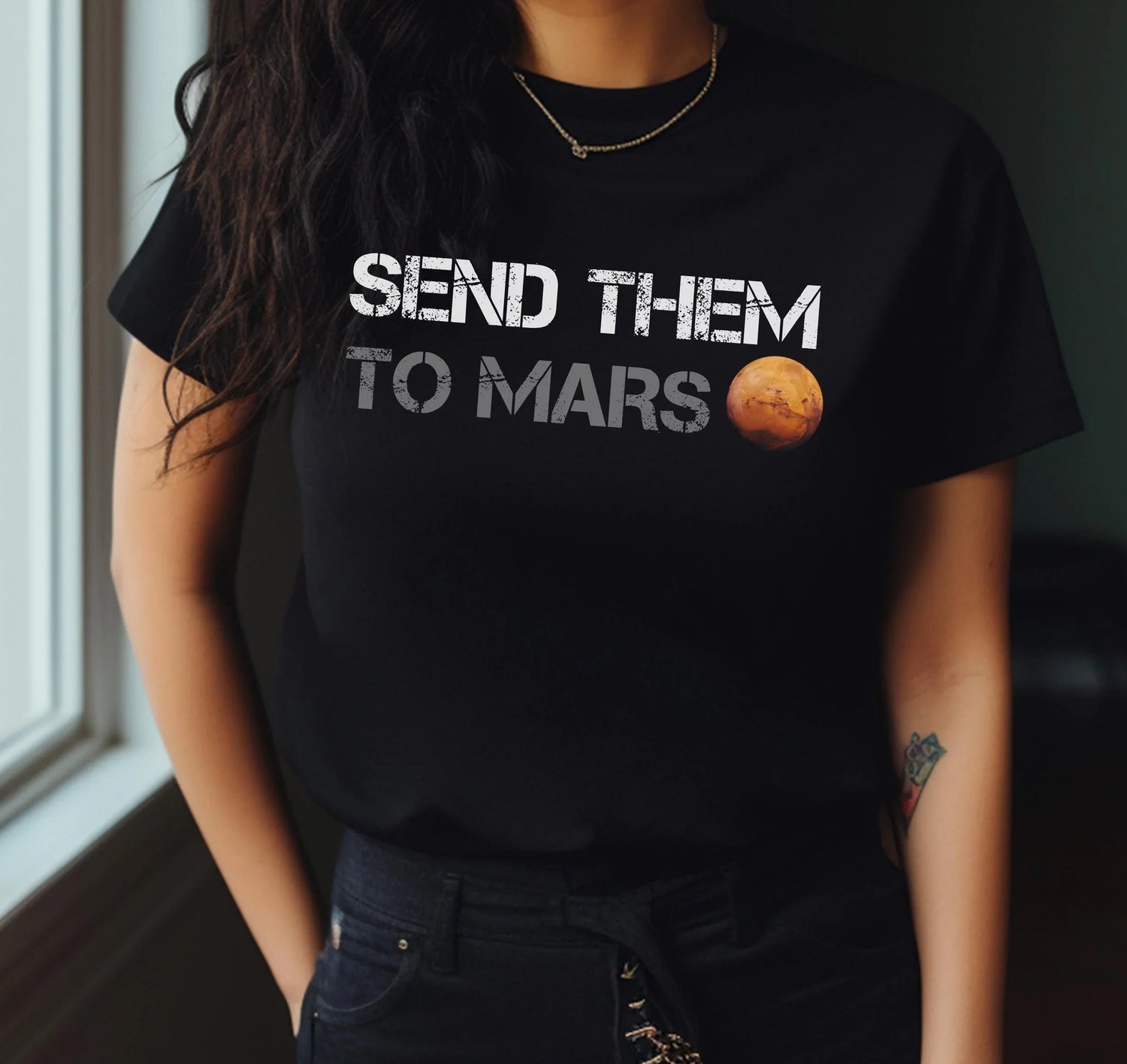 A woman wearing a black t-shirt that says 'SEND THEM TO MARS' with a planet graphic, reflecting themes of Funny Politics.